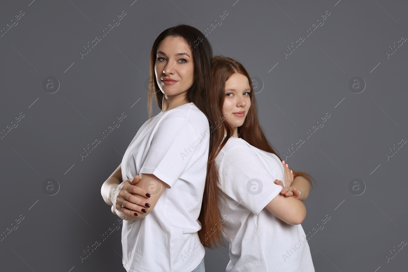 Photo of Portrait of beautiful mother with teenage daughter on grey background