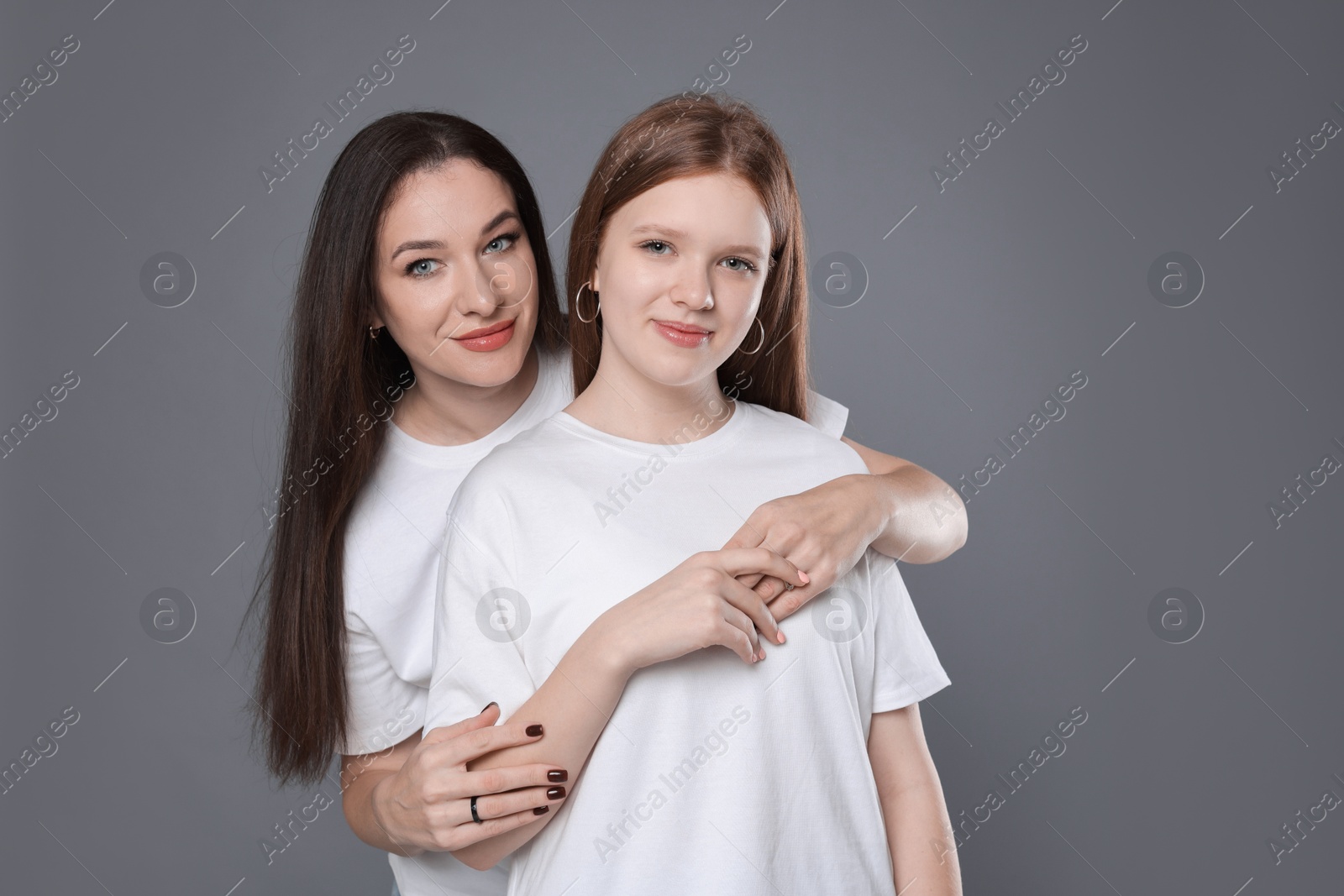 Photo of Portrait of beautiful mother with teenage daughter on grey background