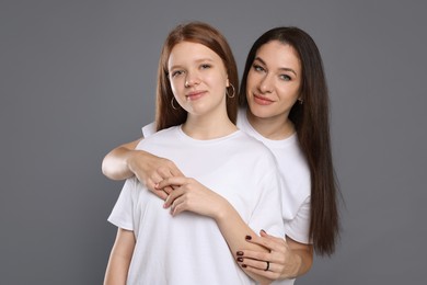 Photo of Portrait of beautiful mother with teenage daughter on grey background