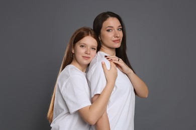 Photo of Portrait of beautiful mother with teenage daughter on grey background