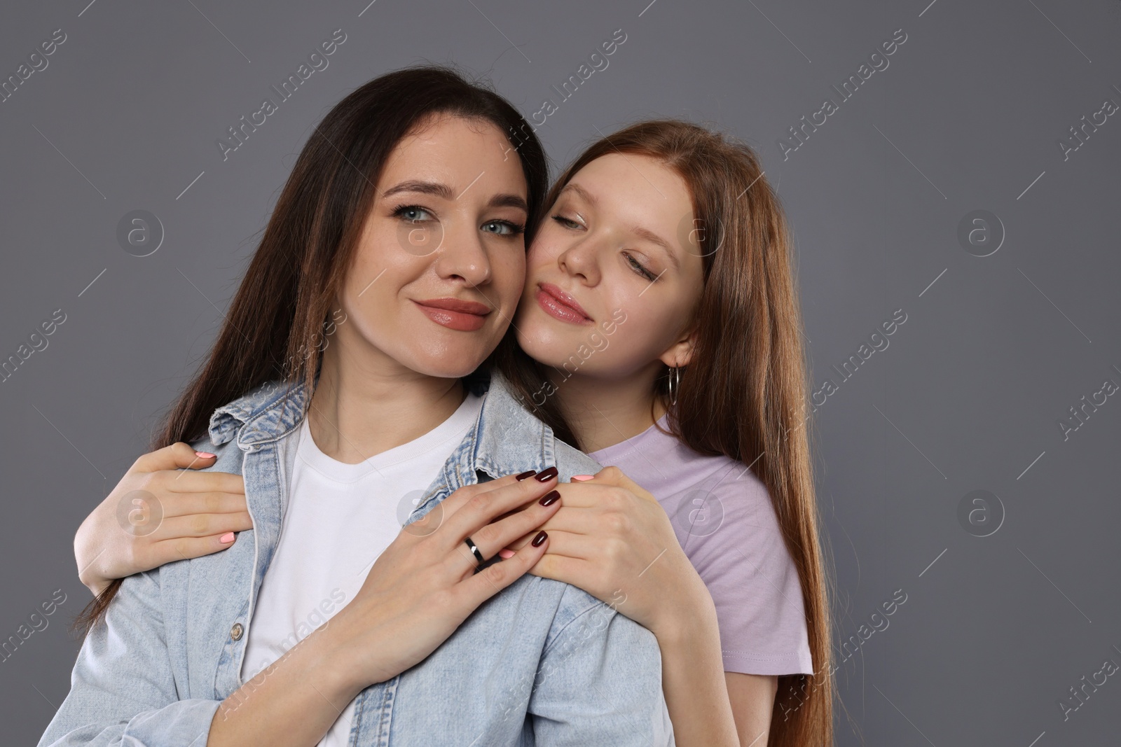 Photo of Portrait of beautiful mother with teenage daughter on grey background