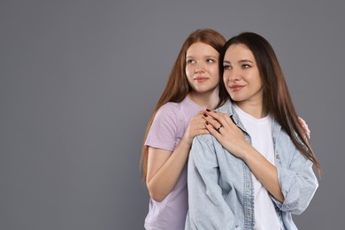 Photo of Family portrait of beautiful mother with teenage daughter on grey background, space for text