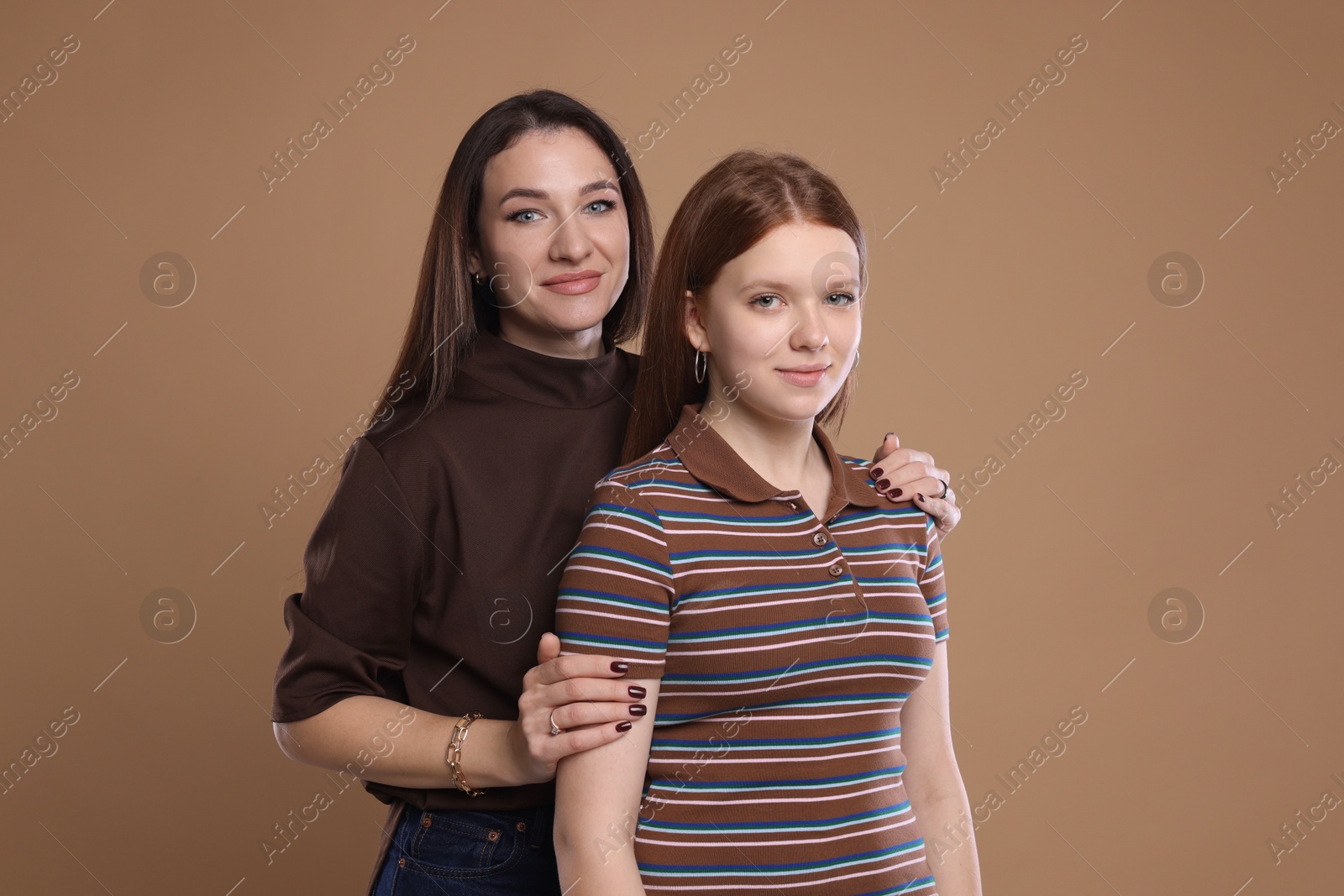 Photo of Portrait of beautiful mother with teenage daughter on dark beige background