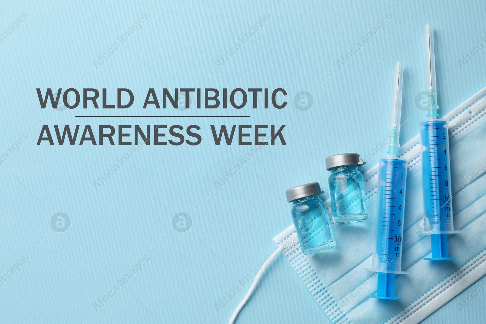 Image of World antibiotic awareness week. Drug in vials, syringes and medical mask on light blue background, flat lay