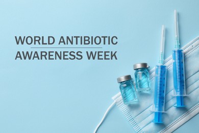 Image of World antibiotic awareness week. Drug in vials, syringes and medical mask on light blue background, flat lay