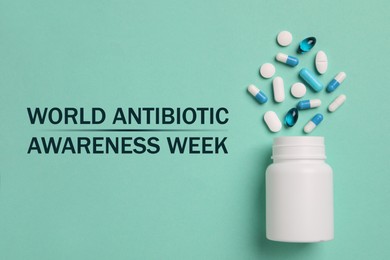 Image of World antibiotic awareness week. Bottle and scattered pills on turquoise background, top view