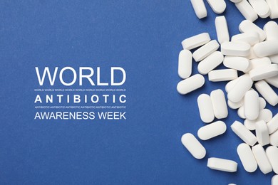 Image of World antibiotic awareness week. Many white pills on blue background, flat lay