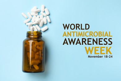 Image of World antimicrobial awareness week. Bottle and scattered pills on light blue background, top view