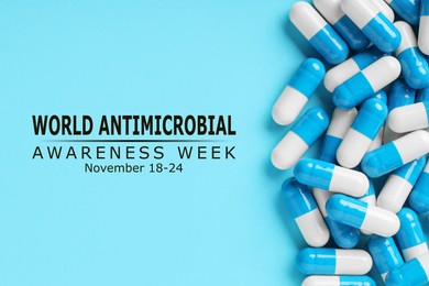 Image of World antimicrobial awareness week. Many pills on light blue background, flat lay