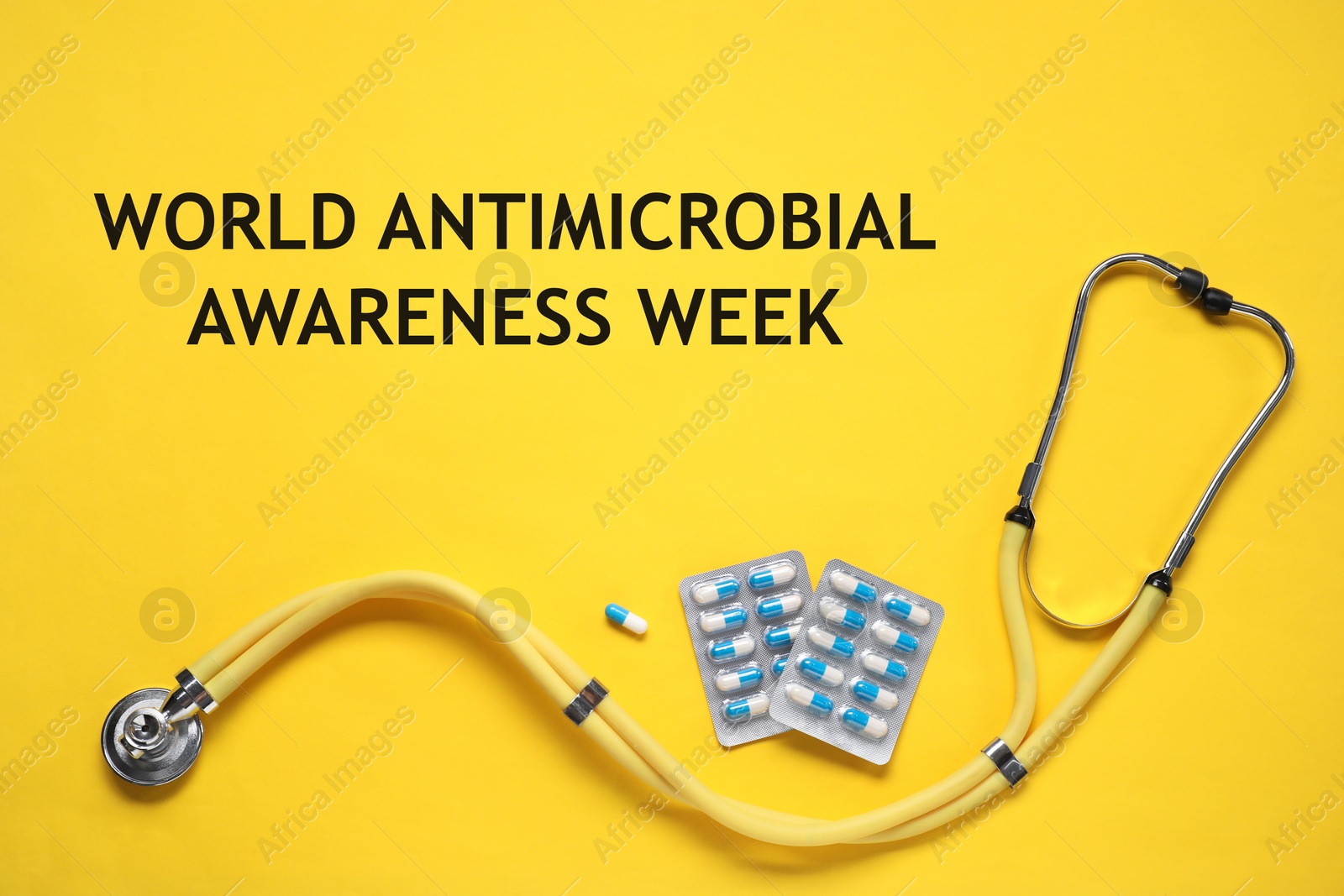 Image of World antimicrobial awareness week. PIlls and stethoscope on yellow background, flat lay