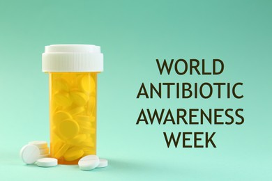 Image of World antibiotic awareness week. Bottle and scattered pills on turquoise background