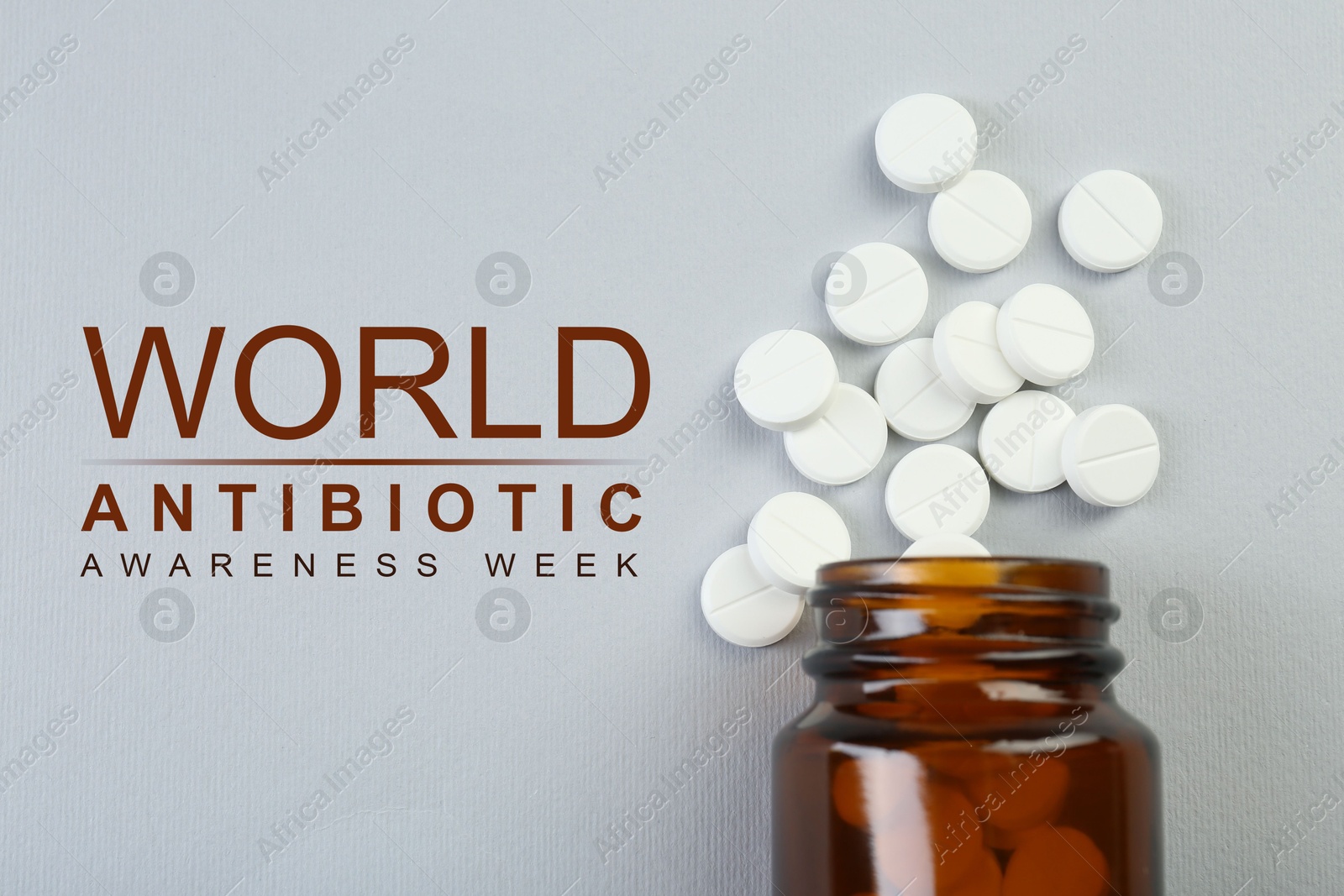 Image of World antibiotic awareness week. Bottle and scattered pills on grey background, top view