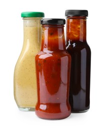 Photo of Different delicious sauces in glass bottles isolated on white