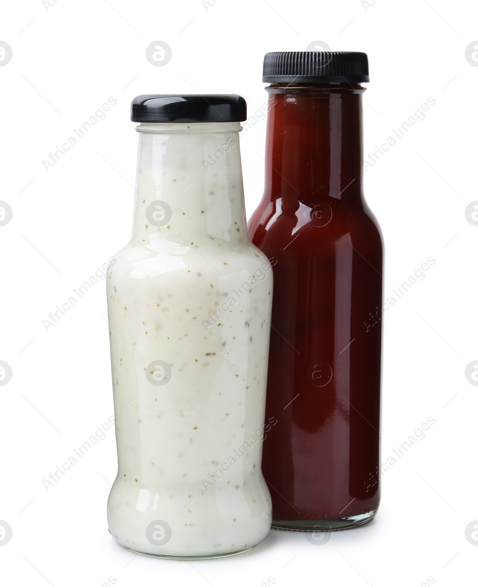 Photo of Different delicious sauces in glass bottles isolated on white