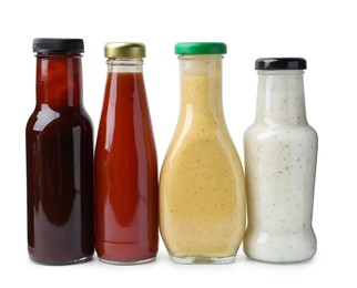 Photo of Different delicious sauces in glass bottles isolated on white