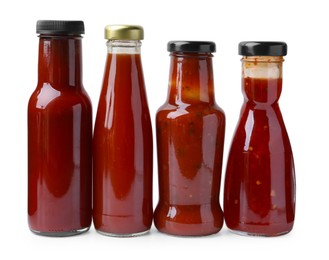 Photo of Different delicious sauces in glass bottles isolated on white