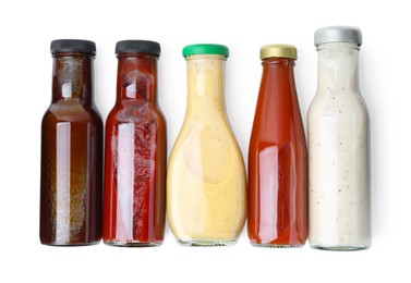 Photo of Different delicious sauces in glass bottles isolated on white, top view