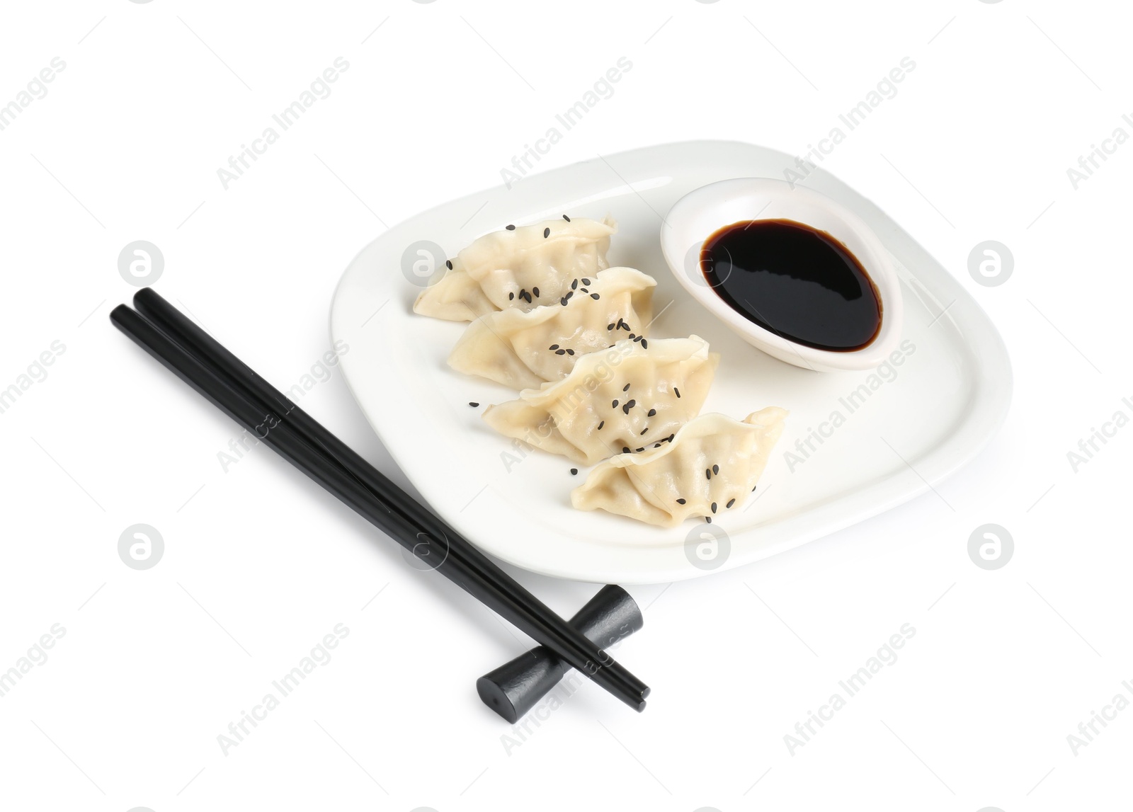 Photo of Tasty gyoza (dumplings), soy sauce and chopsticks isolated on white