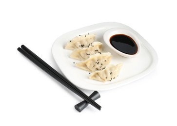 Photo of Tasty gyoza (dumplings), soy sauce and chopsticks isolated on white