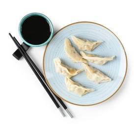 Photo of Tasty gyoza (dumplings), soy sauce and chopsticks isolated on white, top view