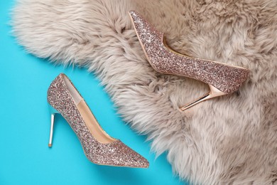 Photo of Beautiful high heeled shoes and faux fur on light blue background, flat lay