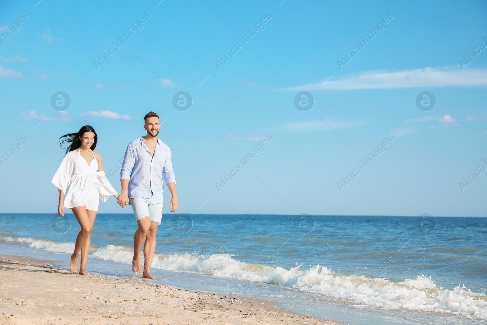 Photo of Happy young couple walking at beach on sunny day