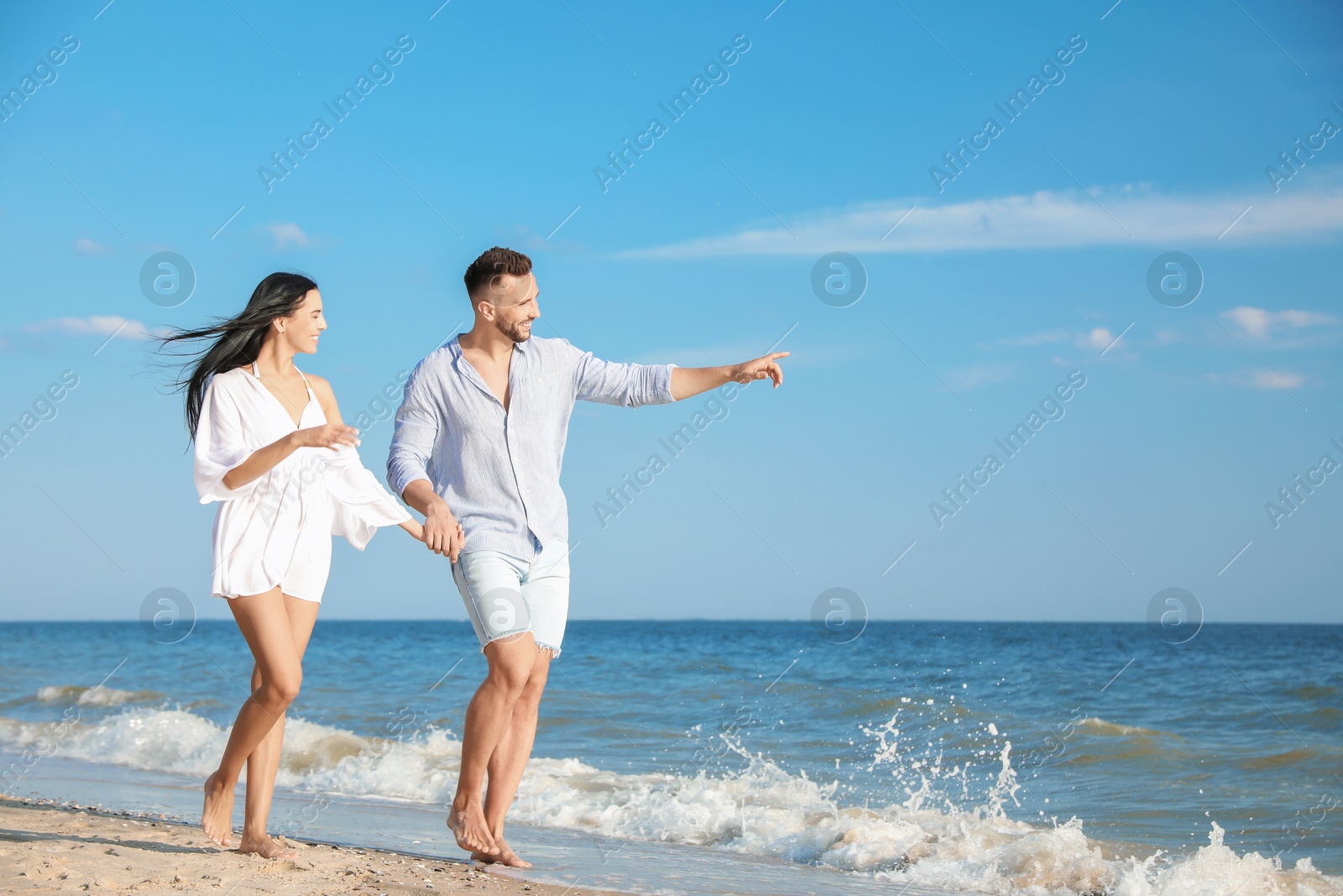 Photo of Happy young couple walking at beach on sunny day