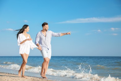 Photo of Happy young couple walking at beach on sunny day