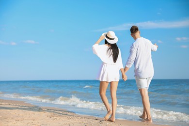 Photo of Lovely young couple walking at beach on sunny day