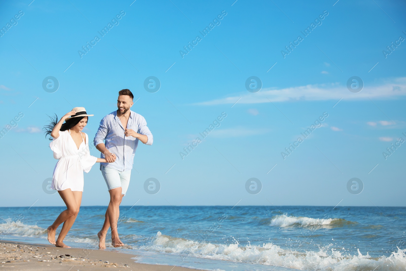 Photo of Happy young couple running together on beach