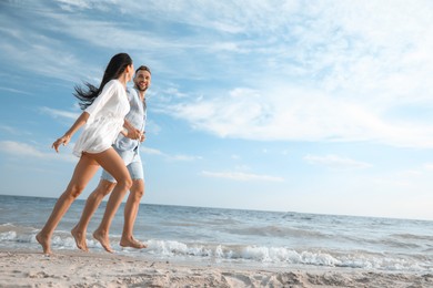 Photo of Happy young couple running together on beach