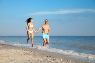 Photo of Happy young couple running together on beach