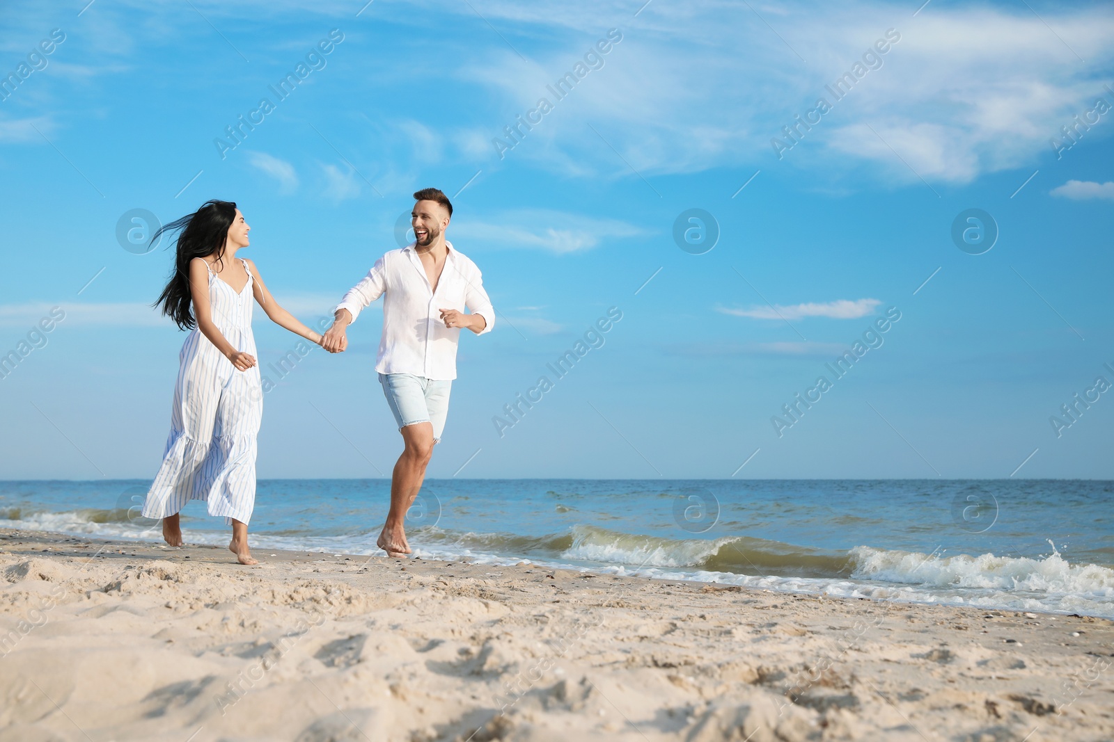 Photo of Happy young couple running together on beach