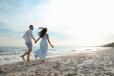 Photo of Happy young couple running together on beach