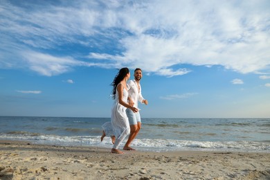 Photo of Happy young couple running together on beach