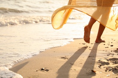 Photo of Young  woman walking on beach at sunset, closeup