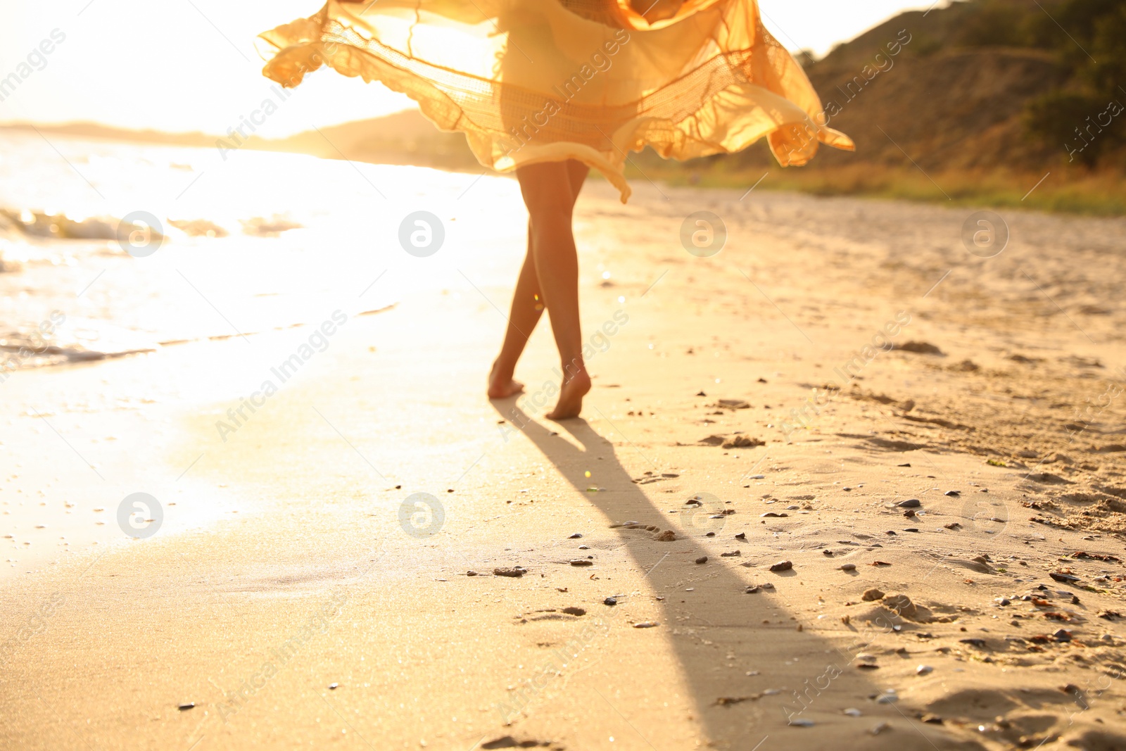 Photo of Young  woman walking on beach at sunset, closeup