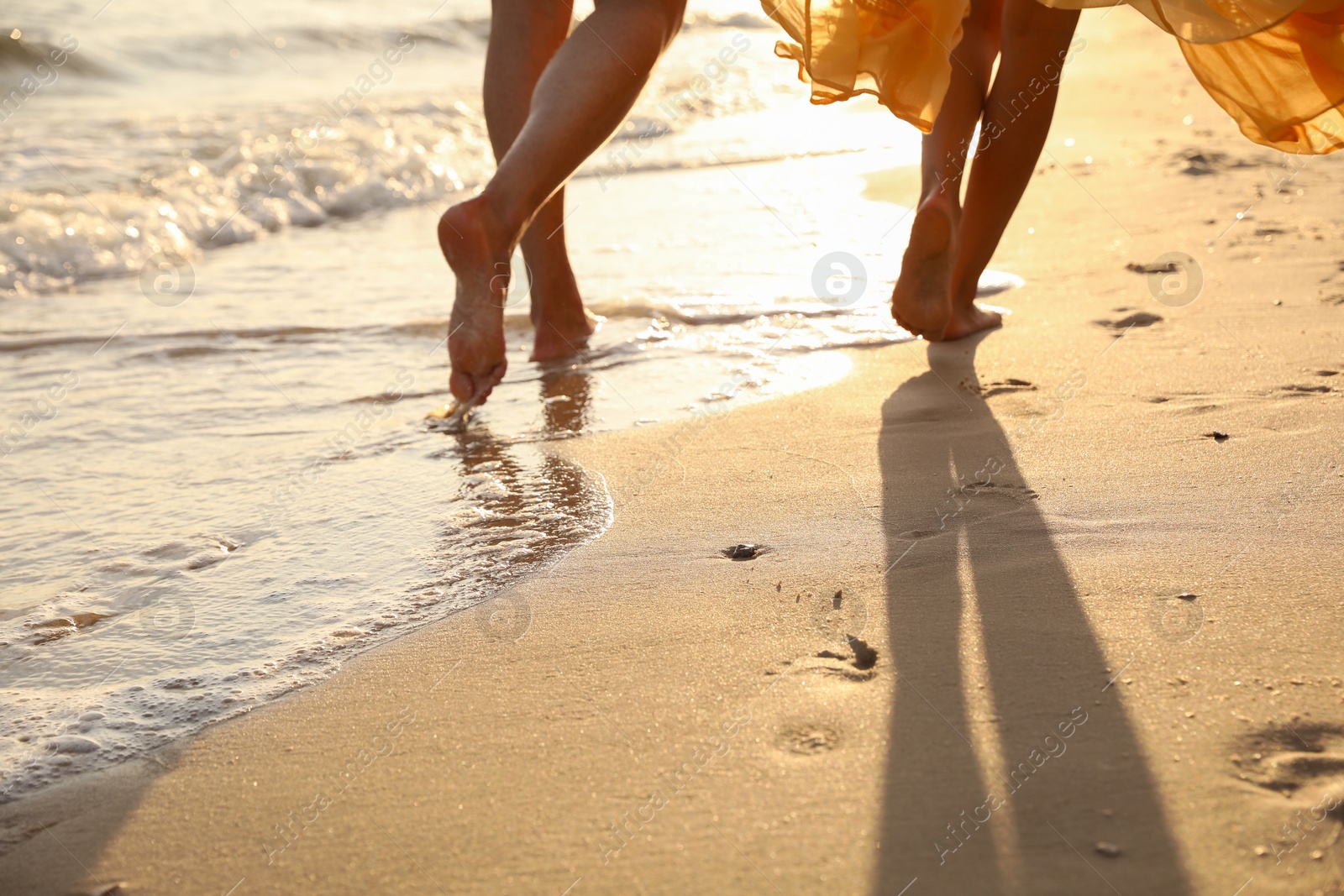 Photo of Couple walking together on beach at sunset, closeup