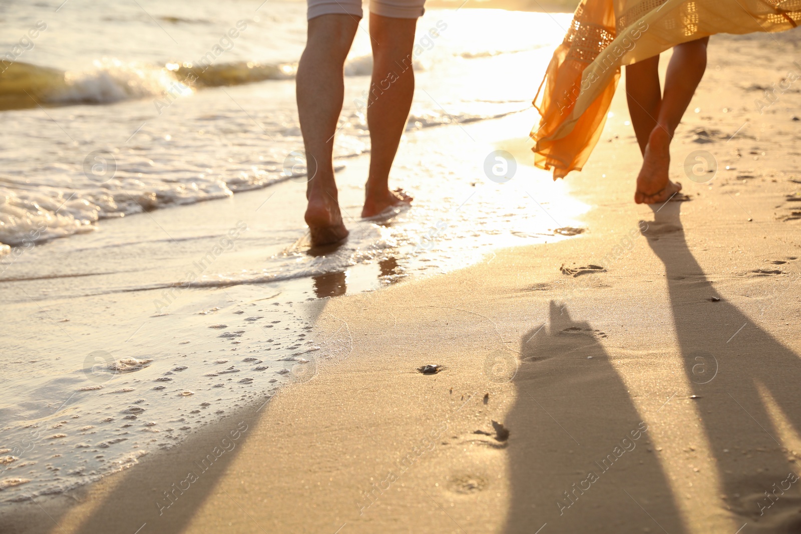 Photo of Couple walking together on beach at sunset, closeup