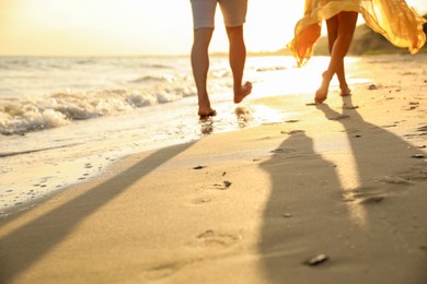 Photo of Couple walking together on beach at sunset, closeup