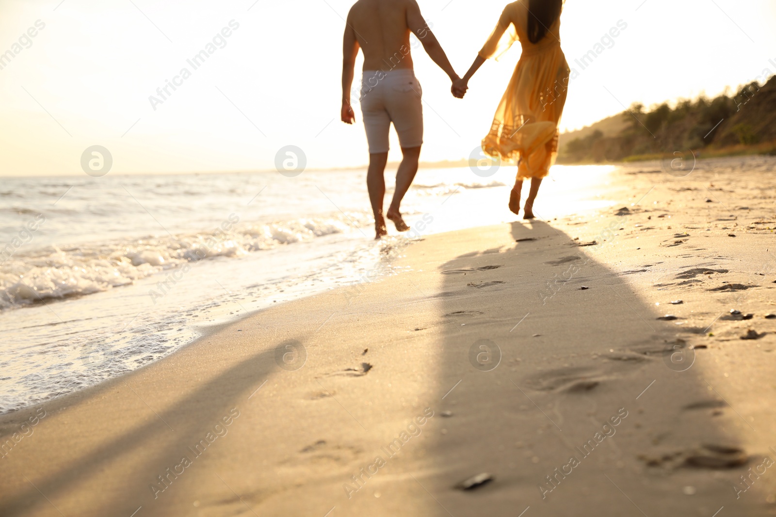 Photo of Couple walking together on beach at sunset, closeup