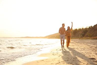 Photo of Happy young couple running together on beach at sunset