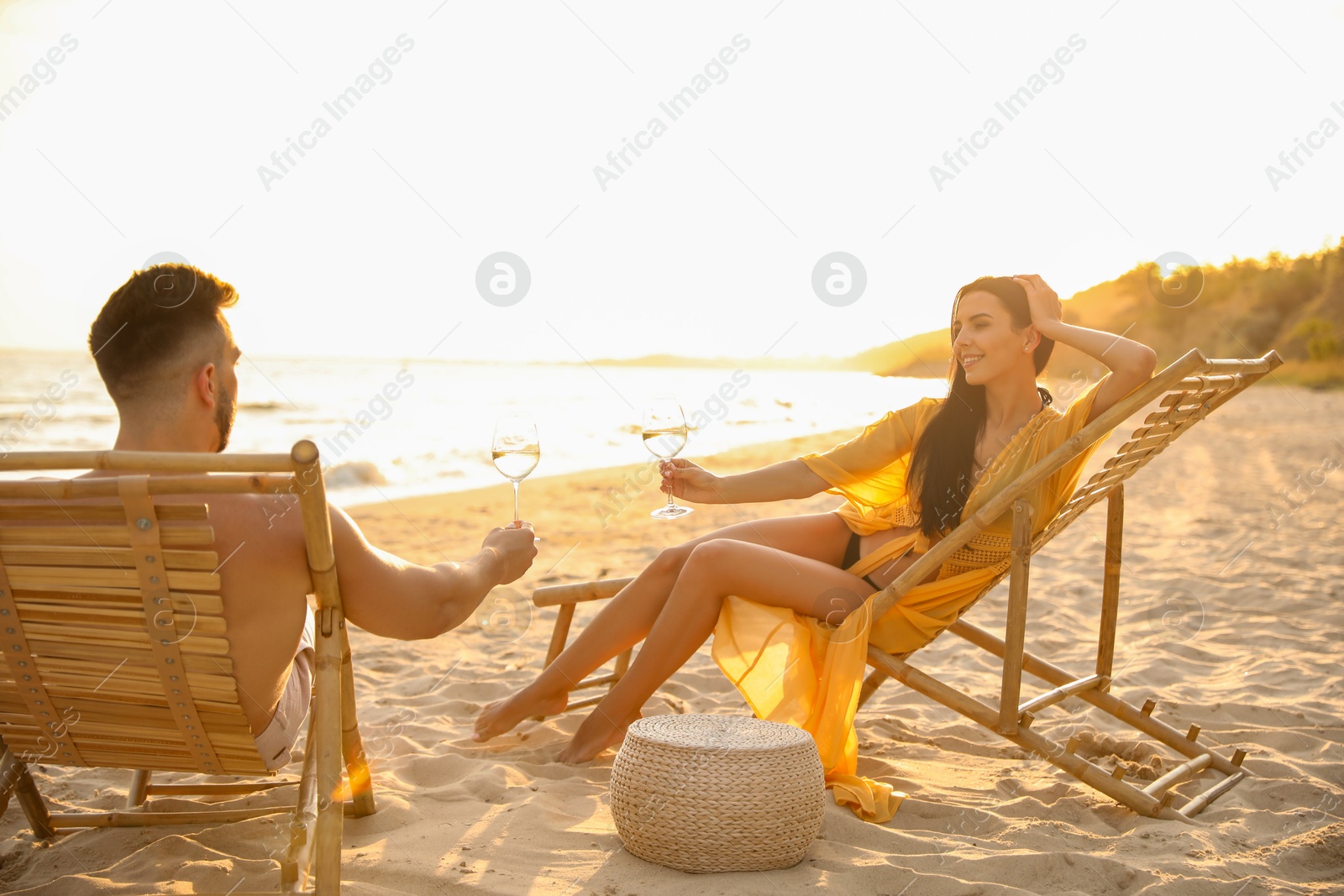 Photo of Romantic couple drinking wine together on beach at sunset