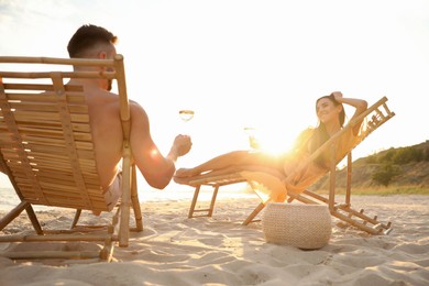 Photo of Romantic couple drinking wine together on beach at sunset