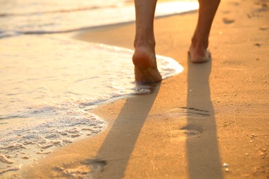 Photo of Man walking on sandy beach, closeup view