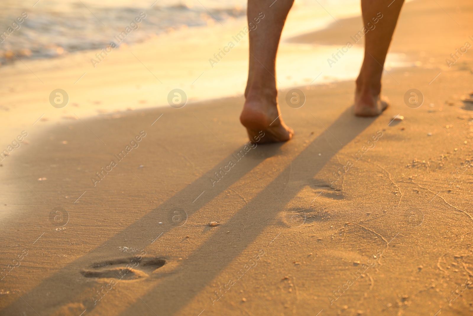 Photo of Man walking on sandy beach, closeup view