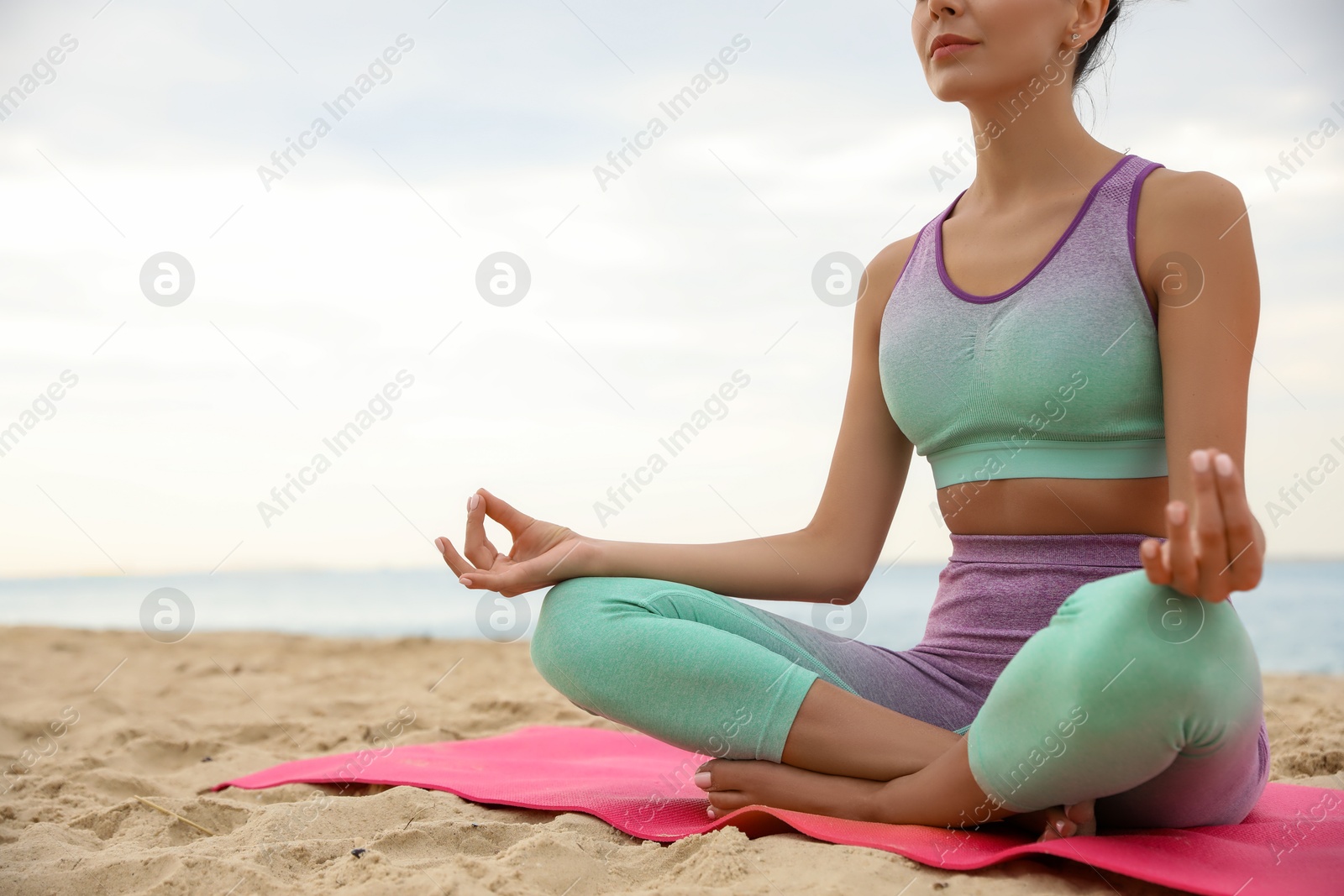 Photo of Young woman practicing yoga on beach, closeup. Body training