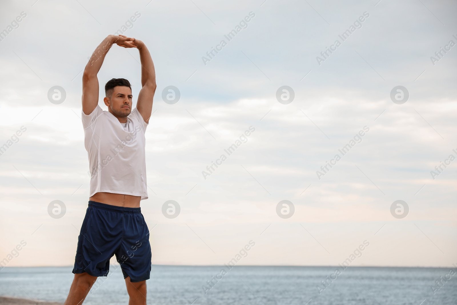 Photo of Muscular man doing exercise on beach, space for text. Body training