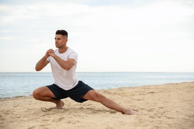 Photo of Muscular man doing exercise on beach, space for text. Body training