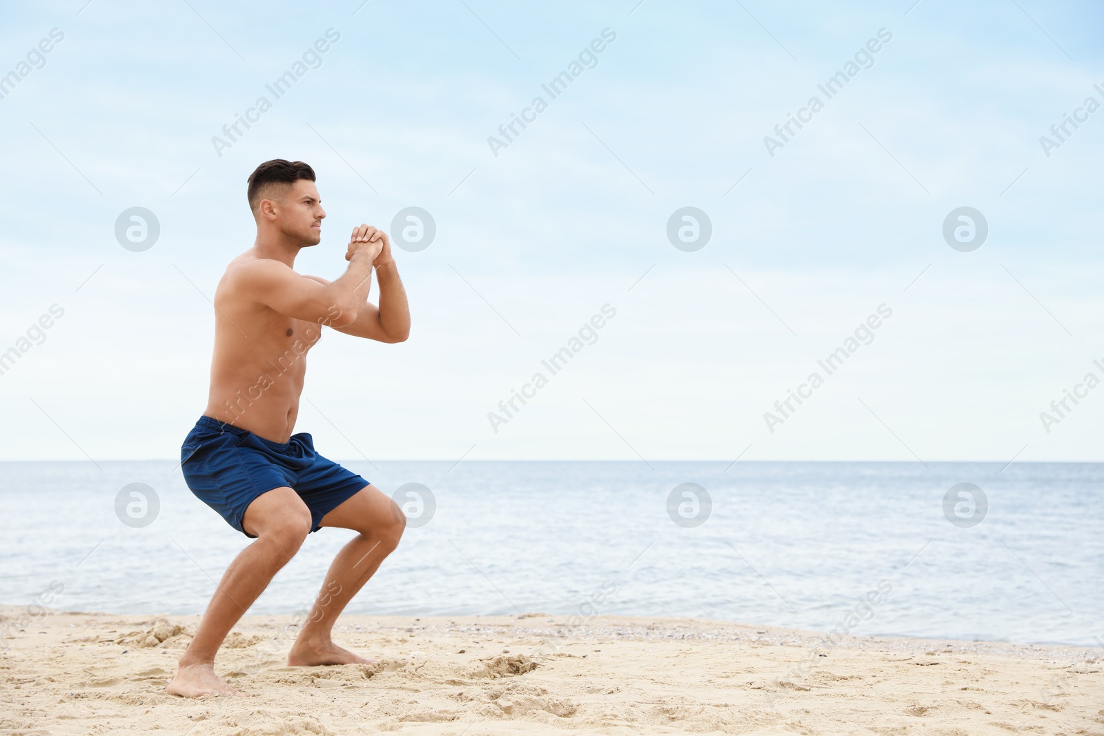 Photo of Muscular man doing exercise on beach, space for text. Body training